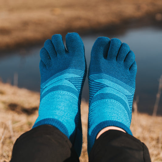Blue toe-separated socks worn outdoors with a natural background